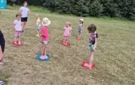 Dzieci stoją w kolorowych szarfach ułożonych na trawie