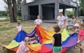 Dzieci biorą udział w zabawie z kolorową chustą animacyjną