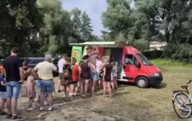 Dorośli z dziećmi stoją w kolejce po lody