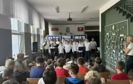 Grupa uczni&oacute;w ubranych w str&oacute;j galowy występuje podczas akademii