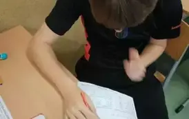 Uczeń siedzi w ławce i wykonuje zadanie