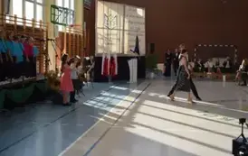 Uczeń i uczennica tańczą, w tle śpiewają uczniowie