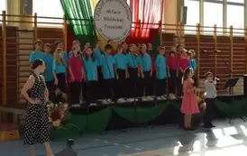 Grupa uczni&oacute;w ubranych na koorowo śpiewa i tańczy