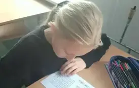 Uczennica siedzi w ławce i rozwiązuje zadanie