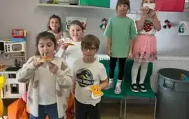 Grupa uczni&oacute;w trzym pizzę w ręku