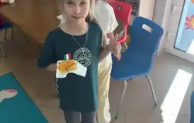 Dziewczynka z pizzą w ręku pozuje do zdjęcia
