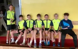 Chłopcy ubrani w stroje sportowe siedzą na ławce i pozują do zdjecia