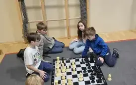 Relaks uczni&oacute;w przed kolejnym pojedynkiem, uczniowie ćwiczą na dużych szachach