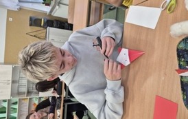 Chłopiec w szare bluzie składa Mikołaja medotą origami