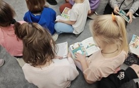 Dzieci siedzą na dywanie i przeglądają książki