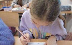 Uczennice siedzą w ławce i szukają par na kartach pracy