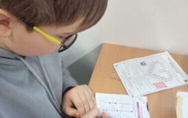 Uczeń siedzi w ławce i wykonuje kartę pracy
