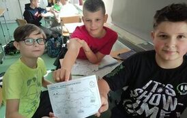 Uczniowie siedzą przy stolikach, rozwiązują zadania, prezentują kartę odpowiedzi.