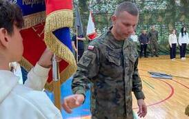 Żołnierz m&oacute;wi do chłopca, kt&oacute;ry trzyma sztandar