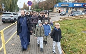 Dzieci-idą-chodnikiem-z-osobą-duchowną-w-sutannie