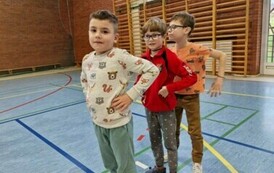 Trzech chłopc&oacute;w na hali sportowej ustawionych jeden za drugim