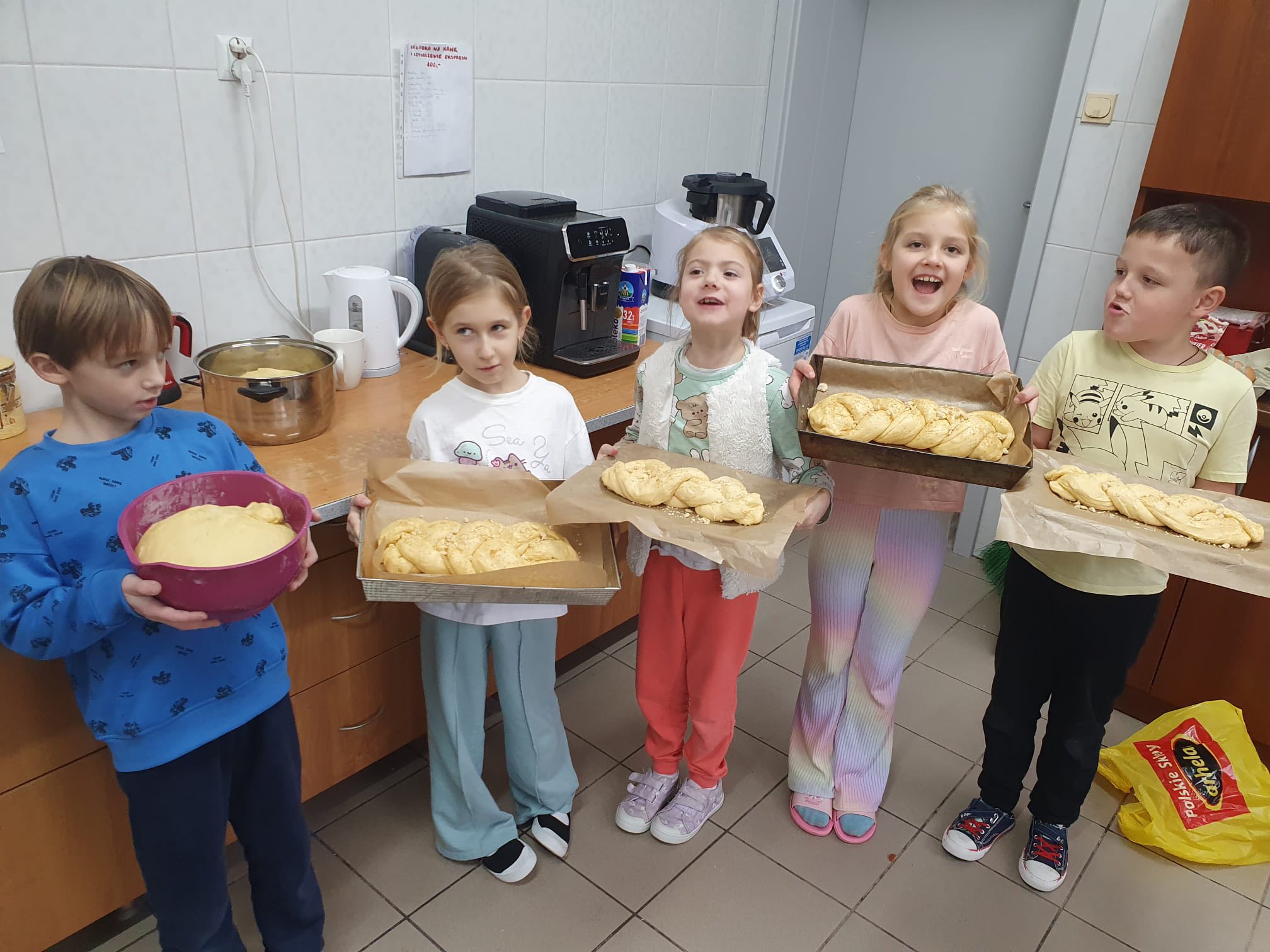 Dzieci prezentują przygotowane do pieczenia chałki